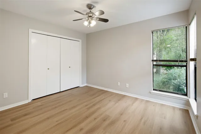 a view of an empty room with a window and wooden floor