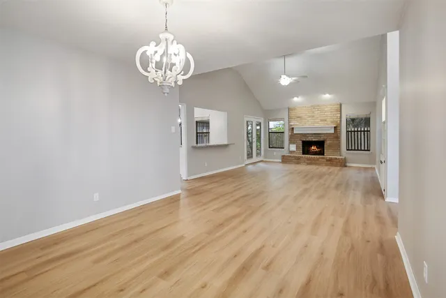 a view of a room with wooden floor fireplace and windows