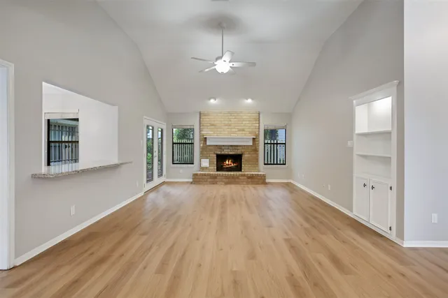 an empty room with fireplace cabinet and windows
