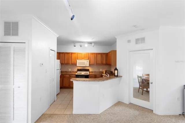 a kitchen with stainless steel appliances a stove top oven a refrigerator a sink a dining table and chairs