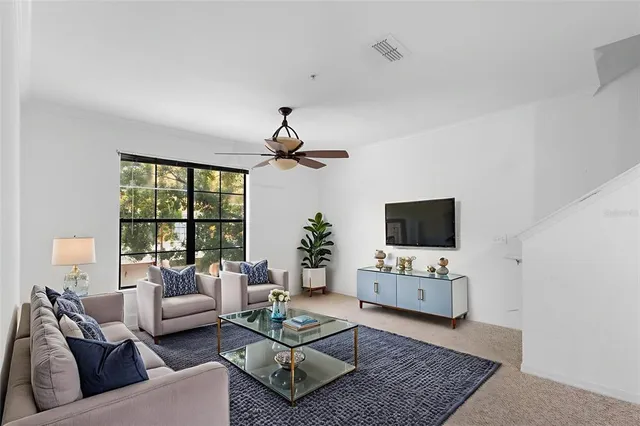 a living room with furniture a flat screen tv and a large window