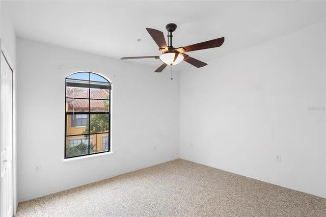 an empty room with windows and fan