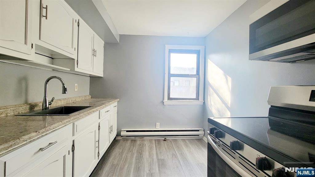 592 Beverly Road, Unit 2 Teaneck, NJ 07666 - Photo 4 of 7 a kitchen with granite countertop a sink and cabinets