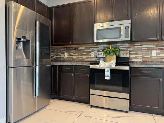 a kitchen with stainless steel appliances granite countertop a refrigerator and a stove top oven