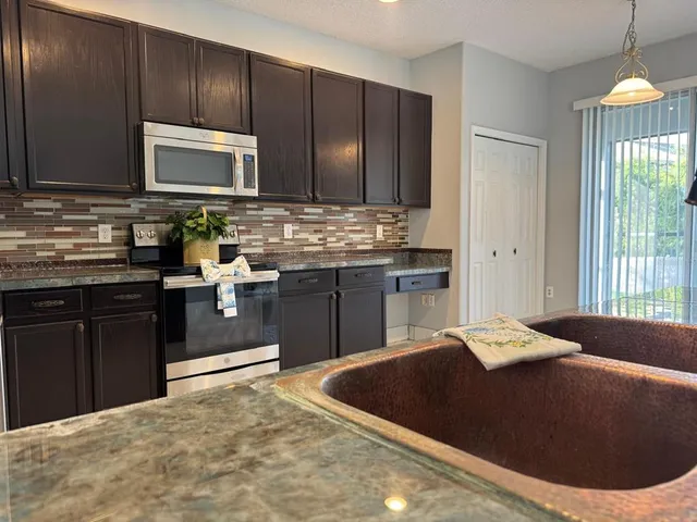 a kitchen with stainless steel appliances kitchen island granite countertop a stove a sink and a microwave