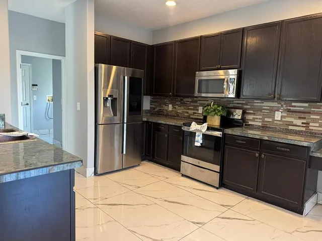 a kitchen with a refrigerator sink and cabinets
