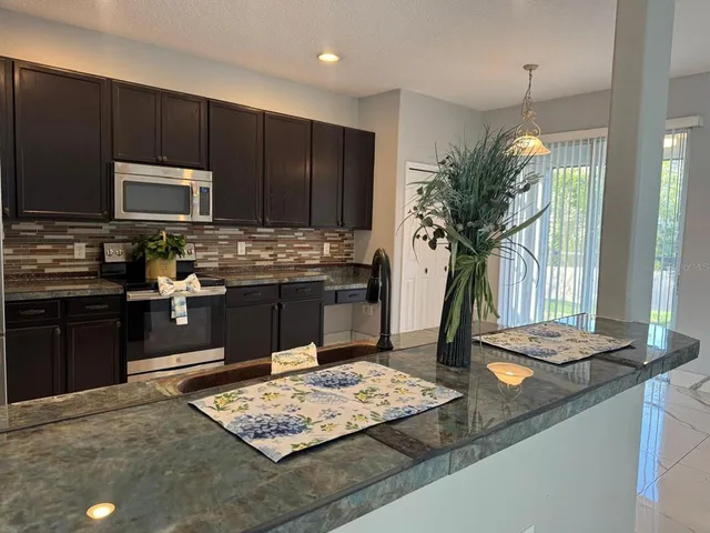 a kitchen with kitchen island granite countertop a stove refrigerator and microwave