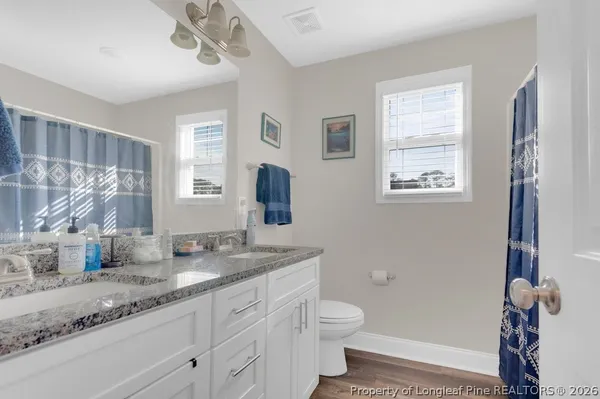 a bathroom with a granite countertop sink toilet a mirror and a window