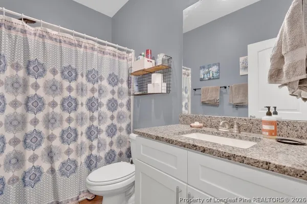a bathroom with a granite countertop sink mirror vanity and toilet