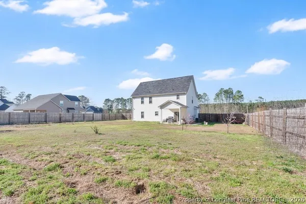 a view of a house with a yard and a large tree