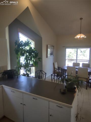 423 Ridge Road Divide, CO 80814 - Photo 15 of 48 Dining Area with a chandelier, vaulted ceiling, white cabinetry, carpet flooring, and pendant lighting