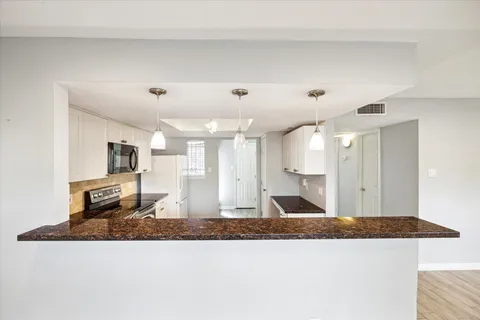 a view of a kitchen with kitchen island a sink wooden floor and living room view