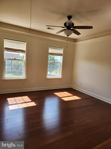 a view of empty room with wooden floor and fan