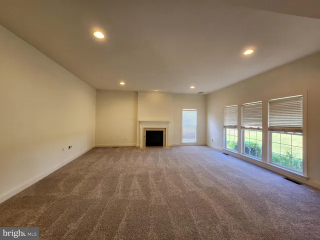 a view of an empty room with a fireplace and a window