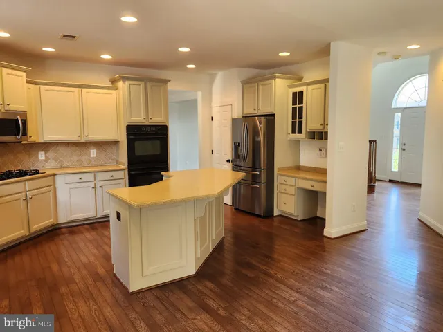 a kitchen with stainless steel appliances a refrigerator and wooden floor