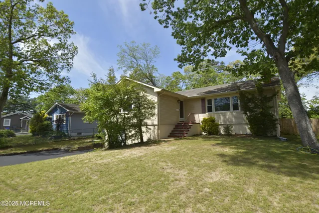 a view of a house with a yard and large tree