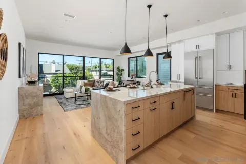 a large kitchen with kitchen island a large counter top a sink a window and chairs