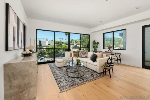 a living room with furniture large windows and wooden floor