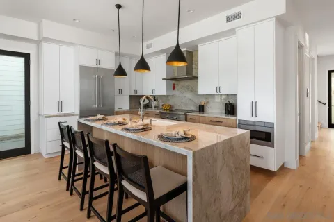 a kitchen that has a kitchen island a stove a table and a refrigerator