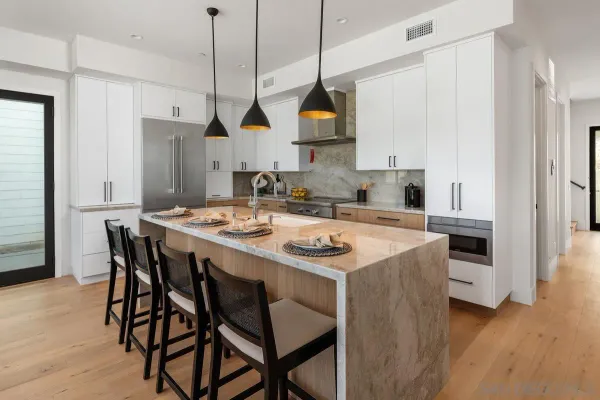 a kitchen that has a kitchen island a stove a table and a refrigerator