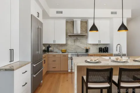 a kitchen with stainless steel appliances granite countertop a stove a sink island and white cabinets with wooden floor