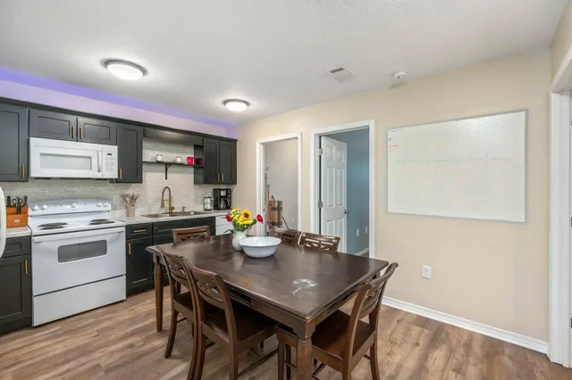 a kitchen with a stove a sink dishwasher a dining table and chairs with wooden floor