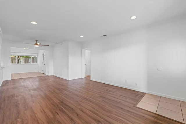 a living room with stainless steel appliances kitchen island granite countertop a stove a sink and a refrigerator with wooden floors