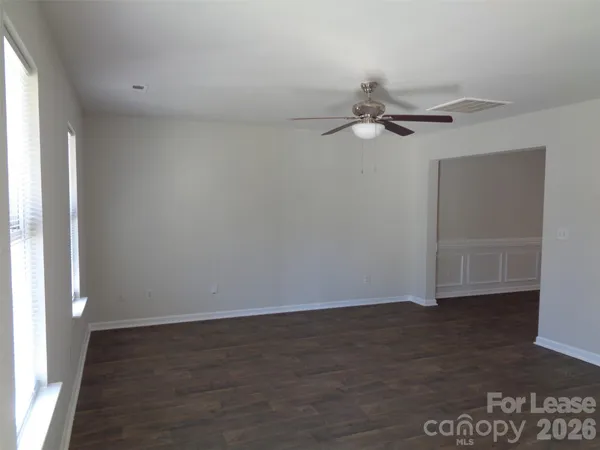 an empty room with wooden floor fan and windows