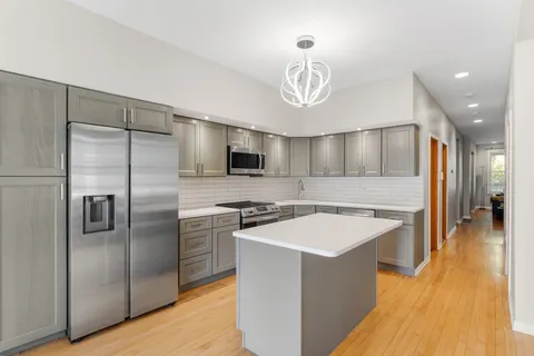 a kitchen with stainless steel appliances a refrigerator a sink dishwasher a stove and a dining table with wooden floor