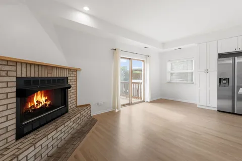 a view of an empty room with wooden floor fireplace and a window