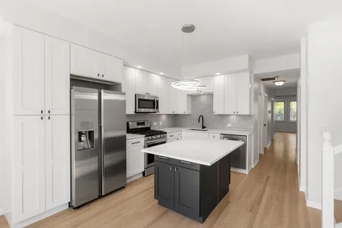 a kitchen with a refrigerator a sink and dishwasher with wooden floor