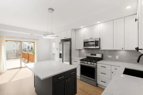 a kitchen with granite countertop white cabinets and stainless steel appliances