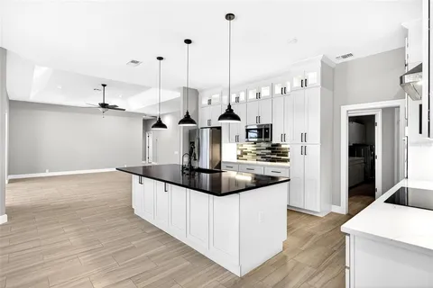 a kitchen with stainless steel appliances granite countertop a sink a stove and a wooden floor
