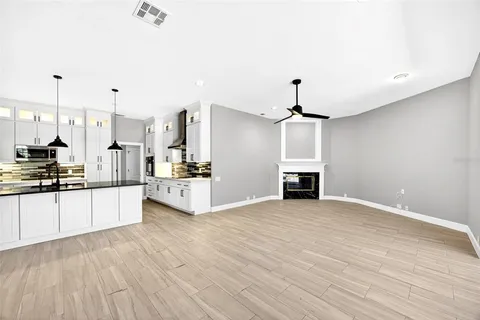 a large kitchen with kitchen island a stove a sink dishwasher and white cabinets with wooden floor