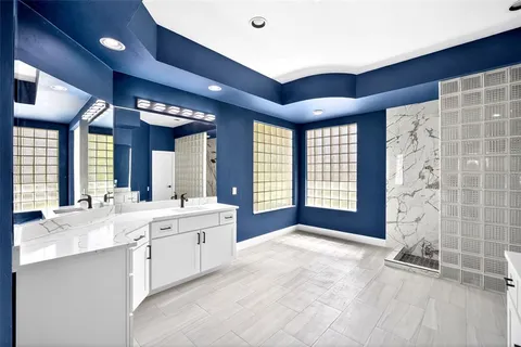 a large room with double vanity sink and natural light