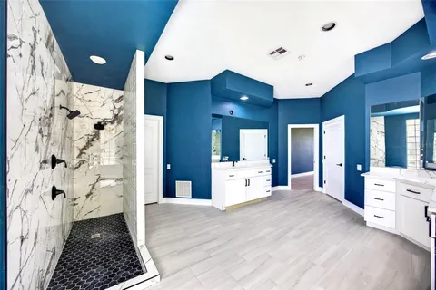 a large bathroom with a glass door shower and a sink