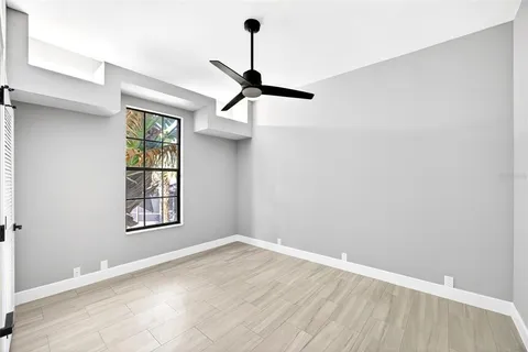 an empty room with wooden floor cabinet and windows