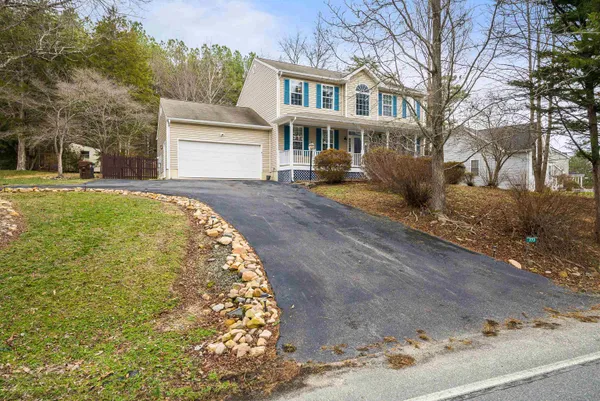 a view of a white house with a yard and large tree and wooden fence