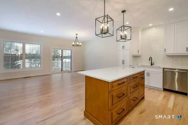 a kitchen with stainless steel appliances a stove a sink a window and wooden floor