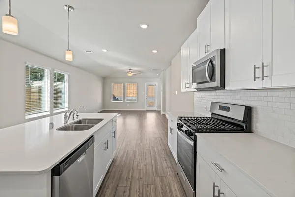 a kitchen with granite countertop a sink a counter space appliances and cabinets