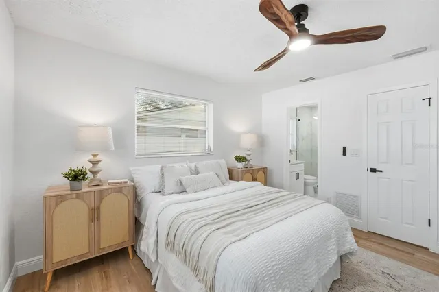 a bedroom with a large bed and a chandelier fan