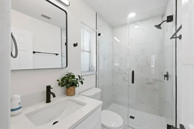 a bathroom with a shower sink vanity and toilet