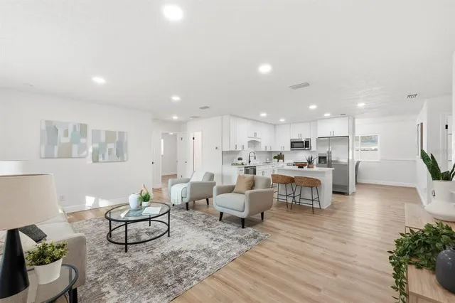 a living room with furniture kitchen view and a wooden floor