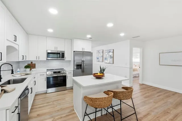 a kitchen with stainless steel appliances a stove a sink a refrigerator cabinets and dining table