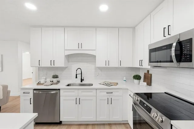 a kitchen with granite countertop a sink stove and white cabinets
