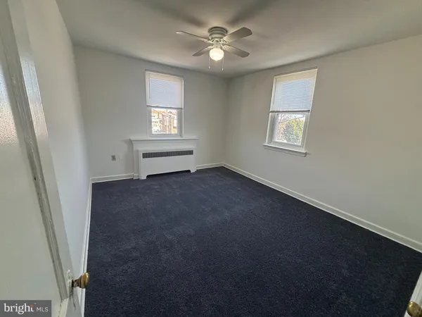 en empty room with windows and ceiling fan