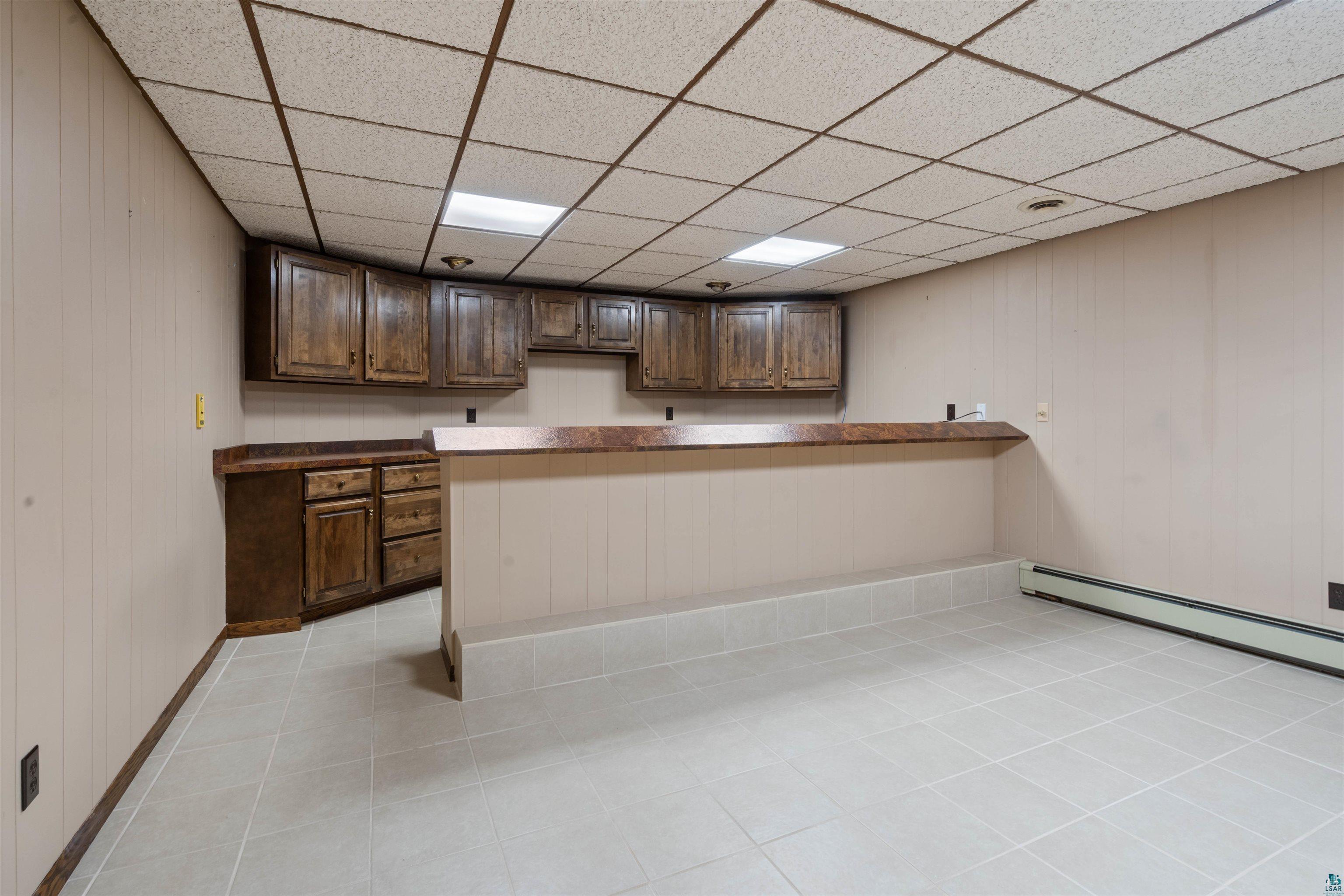 44 Highgate Street Superior, WI 54880 - Photo 15 of 47 Lower level recreation space featuring tile flooring and a built-in bar with wood cabinetry and a laminate countertop