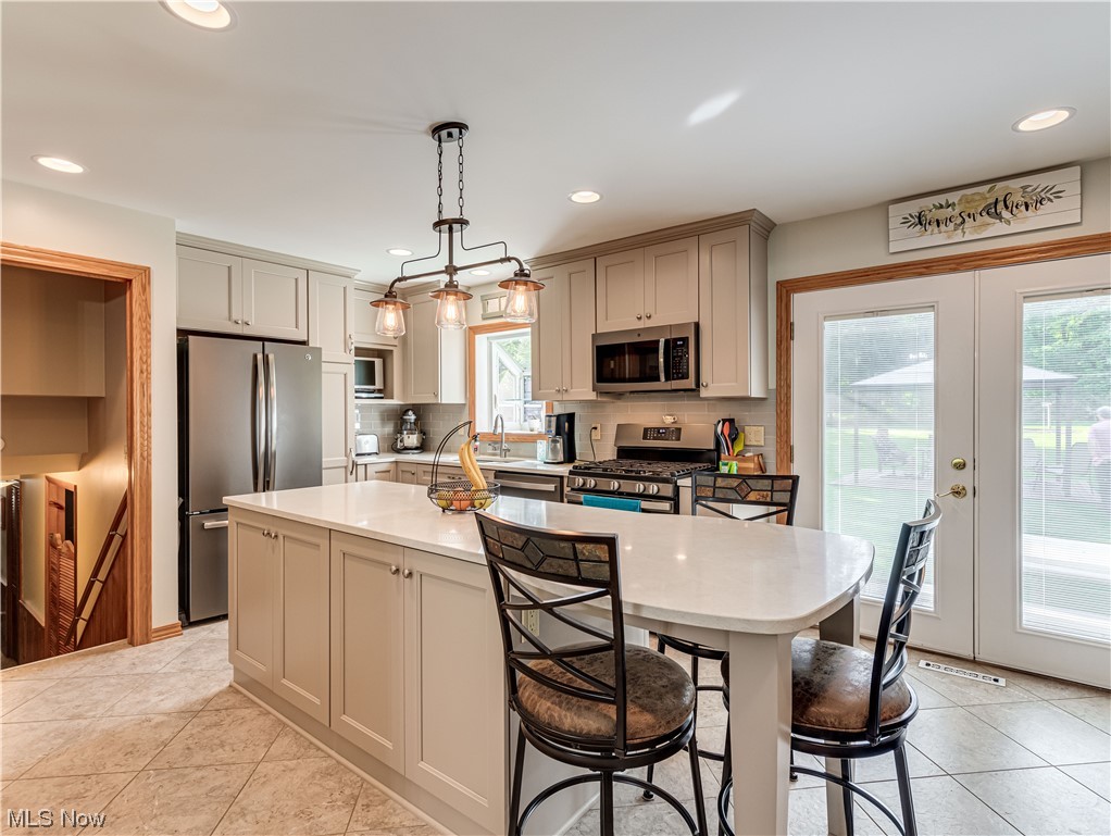 5200 Skinner Road Mantua, OH 44255 - Photo 2 of 23 Kitchen with backsplash, white cabinets, light countertops, appliances with stainless steel finishes, a center island, and light tile flooring