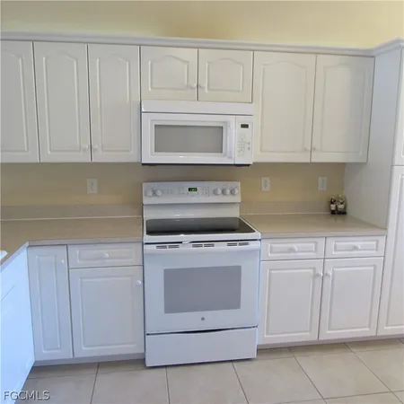 a kitchen with white cabinets and white appliances