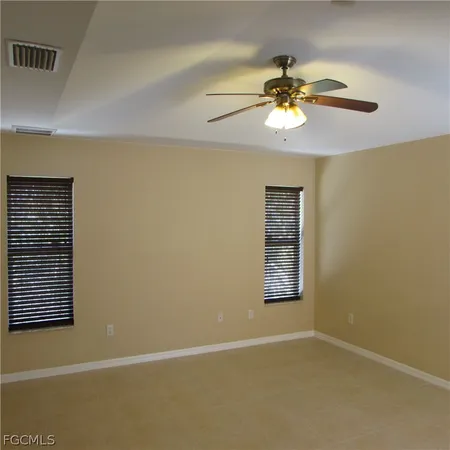 an empty room with windows and chandelier fan